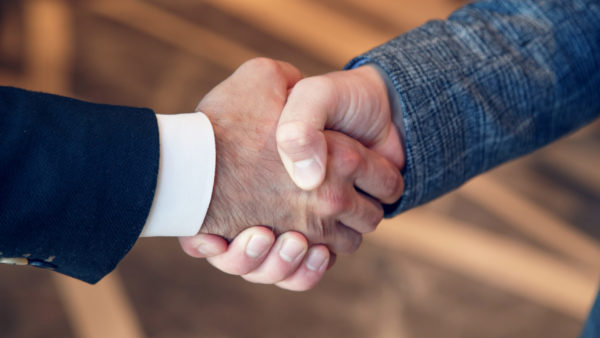 Men shake hands at business meeting.